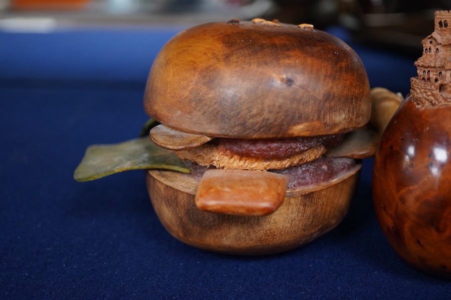 Pierre Decorse (b.1953), two carved wooden sculptures, an egg with a miniature town emanating from its top; and a stylised burger, largest 14cm wide